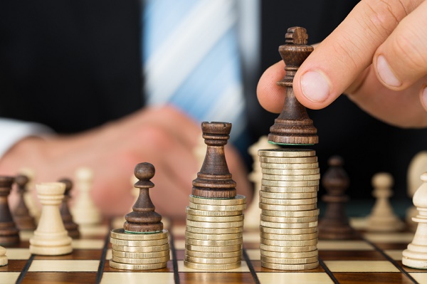 Businessman Placing Chess Pieces On Stacked Coins