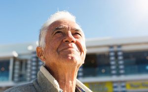 Smiling senior man looks up at sky, relaxed and contented