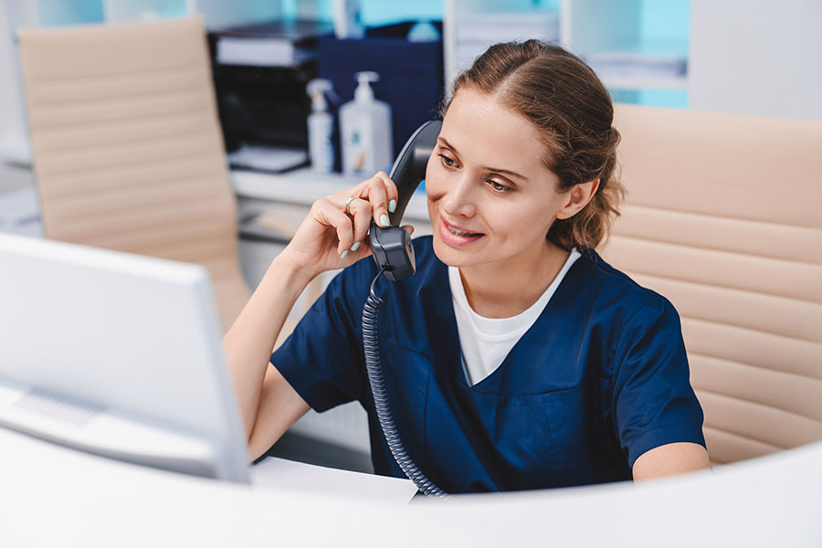 Front desk staff woman scheduling a patient appointment on the phone.