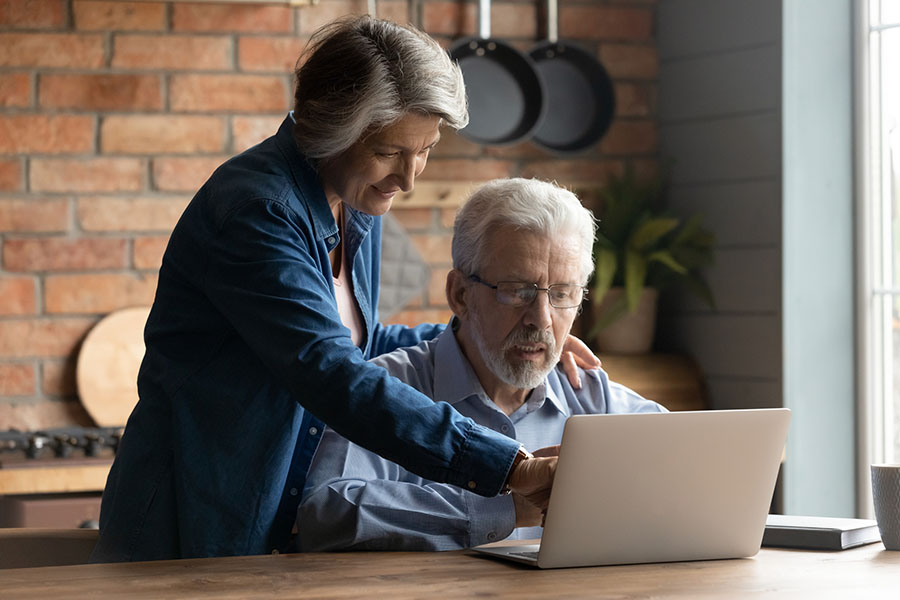 Woman helping a senior man search for a medical practice online.